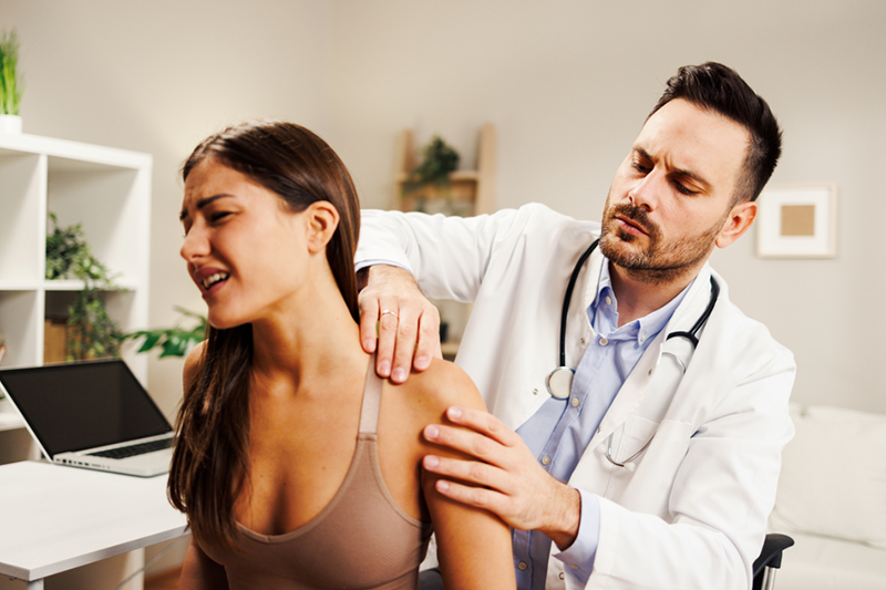 Young Lady at the doctor with shoulder pain.