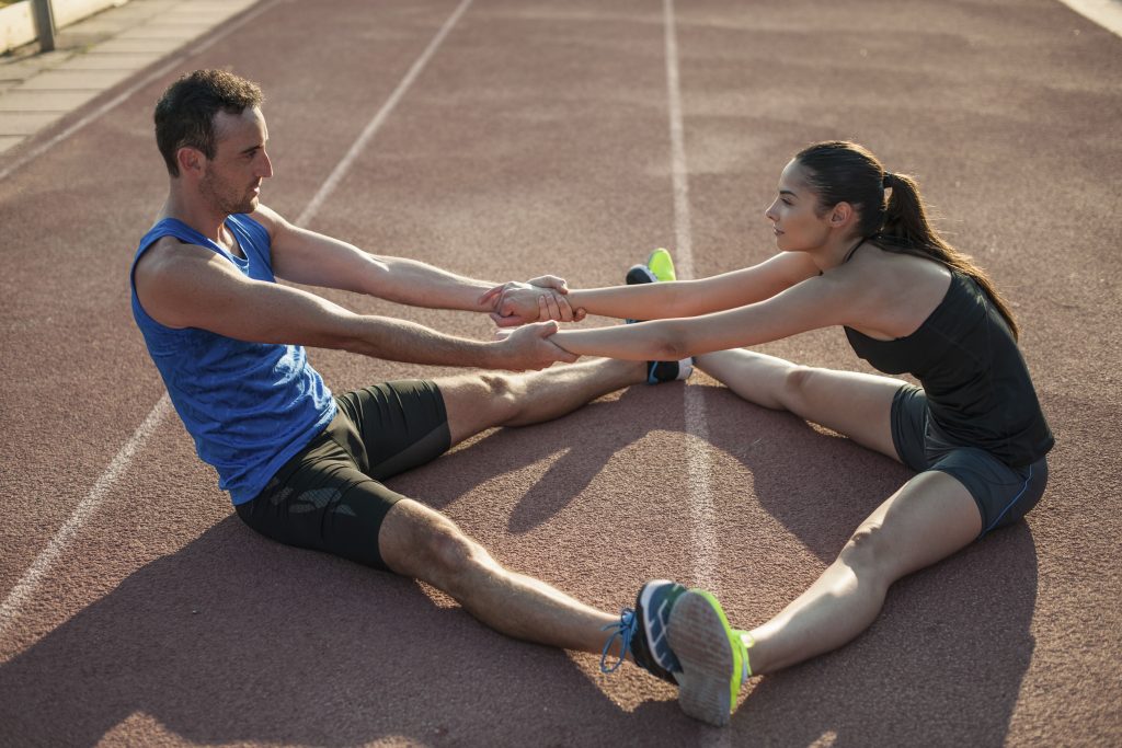 Adult Athletes Stretching Together